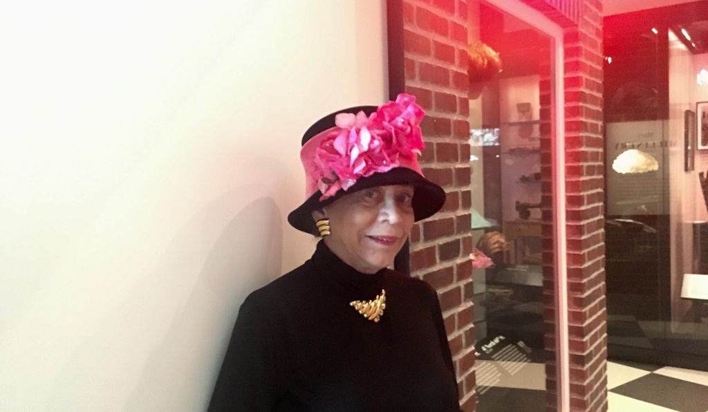 Donna Limerick wears a replica of one of her mother's hat designs while visiting the Mae's Millinery Shop exhibit at the National Museum of African American History and Culture.